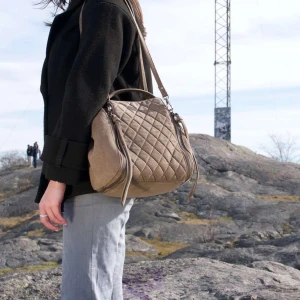 Beige axelväska - Snygg beige axelväska. Perfekt för att bära med sig det nödvändigaste. Väskan har en praktisk axelrem.