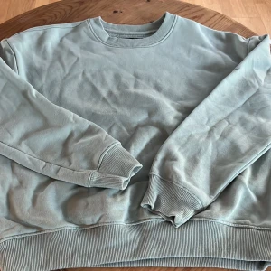 Ljusblå sweatshirt - Säljer en bekväm ljusblå sweatshirt med rund hals och långa ärmar.  Tröjan har ribbade muddar vid ärmslut och nederkant.