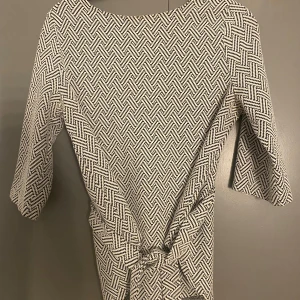 Mönstrad klänning från KappAhl - Snygg mönstrad klänning från KappAhl i svart och vit. Klänningen har trekvartsärmar och ett geometriskt mönster som ger en stilren look. Perfekt för både vardag och speciella tillfällen.