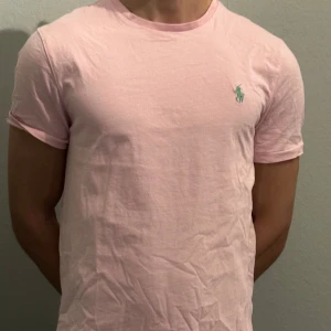 Rosa t-shirt från Ralph Lauren - Säljer en stilren rosa t-shirt från Ralph Lauren! Killen på bilden är 180 och sitter en aning tajt! Passar perfekt till Pink party!