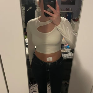 Vit långärmad topp - Säljer en stilren vit croppad topp med lång ärm och en unik cut-out detalj vid halsen. Perfekt för en trendig look.💕