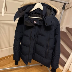Canada goose vinterjacka - Säljer en mörkblå dunjacka från Canada Goose med avtagbar huva och pälsdetalj. Modellen heter Wyndham Parka. Perfekt för kalla vinterdagar. Storlek: S/M. Osäker om den är oäkta därav priset.