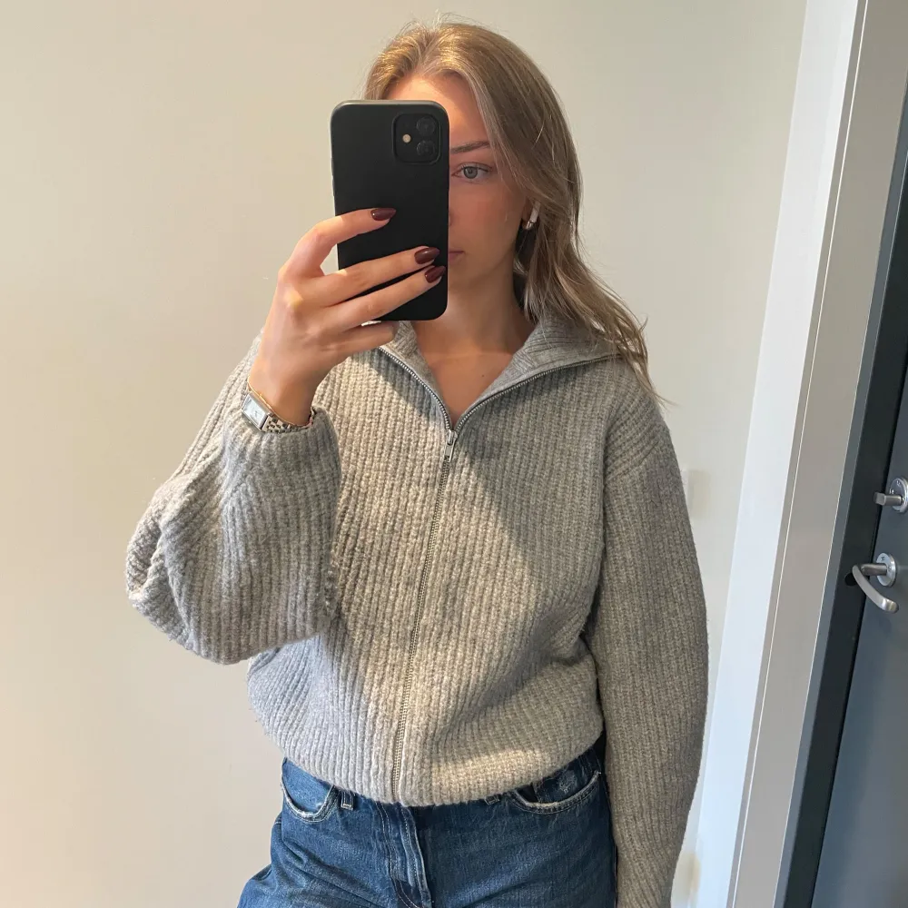 Säljer en mysig grå stickad tröja från BikBok med dragkedja framtill. Tröjan har en hög krage och långa ärmar, perfekt för kyliga dagar. Den ribbade strukturen ger en stilren look. Passar bra till jeans eller kjol.. Neuletakit & Villapaidat.