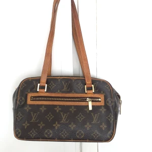 Äkta Louise Vuitton axelväska  - Säljer en axelväska från Louis Vuitton med det klassiska monogrammönstret och axelremmar i läder. Köpt second hand av Care of Carl som garanterar äkthet där alla väskor kontrolleras av experter innan försäljning till ett pris av 7000kr. Den är god kvalite, lite slitningar på dragkedjan (se sista bilden) och spår av användning på axelremmar men annars mycket god kvalite och kommer hålla många år till. Kan ses i Stockholm om du vill känna på den innan köp.