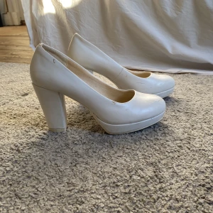 Vita pumps från Attitude - Säljer ett par stilrena vita pumps från Attitude med hög klack och rund tå. Perfekta för en elegant look. Skorna har en klassisk design som passar till många tillfällen.