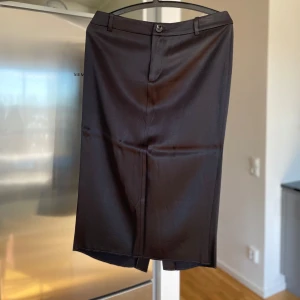 Svart pennkjol från Mango - Svart pennkjol från Mango med en stilren design. Kjolen har en diskret slits baktill och stängs med dragkedja och knapp framtill. 