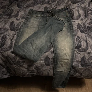 Blå jeans från Jack & Jones - Säljer ett par snygga blå jeans från Jack & Jones, modell Slim/Glenn. De har en slim passform och klassisk femficksdesign. Perfekta för en stilren look. Storlek 26-30