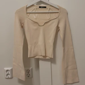 Beige ribbad topp från Gina Tricot - Säljer en stilren beige ribbad topp från Gina Tricot. Toppen har en unik halsringning och långa ärmar. Perfekt för en shick och enkel look. Passar bra till både jeans och kjol. 🧡Priset kan diskuteras. 