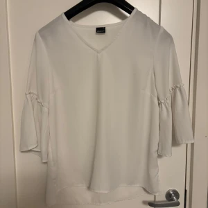 Vit blus från Gina Tricot - Säljer en vit blus från Gina Tricot med v-ringning och trekvartsärmar. Blusen har volangdetaljer vid ärmarna som blir perfekt för både vardag och speciella tillfällen. Den är i storlek 36 men skulle säga att den är väldigt stor i storleken. Vill ni ha bättre bilder så är det bara och skriva. Pris kan diskutera!💗💗