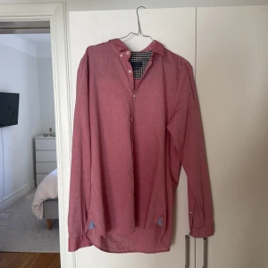 Rosa skjorta från Zara Man - Snygg rosa skjorta från Zara Man i slim fit. Skjortan har långa ärmar och knappar framtill. Insidan av kragen har ett stilrent rutigt mönster i svart och vitt. Perfekt för en stilren look.