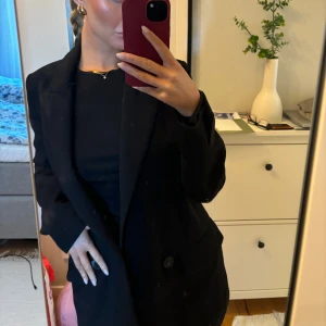 Svart kavaj - Snygg svart kavaj med klassisk design och knappar framtill. Perfekt för en stilren look.