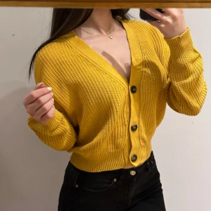 Ribbad kofta från 157 - Gul ribbad kofta från 157. Den har en v-ringning och knappar framtill, i storlek s. 