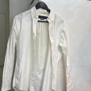 Vit skjorta från Ralph Lauren - Säljer en klassisk vit skjorta från Ralph Lauren med button-down krage och broderad logga på bröstet. Skjortan har långa ärmar och knappar framtill. Perfekt för en stilren look.