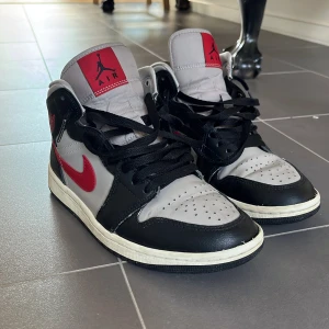 Nike Air Jordans i svart, grå och röd - Säljer ett par klassiska Nike Air Jordans i svart, grå och röd. Skorna har en ikonisk design med snörning och rund tå. Perfekta för dig som älskar sneakers med stil och komfort. Skorna är lite creasade men i bra skick. Nypris runt 1700kr mitt pris:800kr