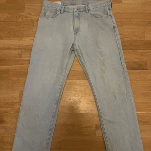 Ljusblå jeansbyxor - Säljer ett par ljusblå jeansbyxor med klassisk femficksdesign och knappgylf. Byxorna har en rak passform och är tillverkade i denim. Perfekta för en avslappnad stil. Lite defekter (se bilder i slutet) där av det låga priset! Relaxed fit. 36/32