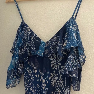 Ny Mönstrad långklänning från Polo Ralph Lauren med lapp kvar - Säljer en elegant långklänning från Polo Ralph Lauren i mörkblått med ett vackert blommigt mönster. Klänningen har volangdetaljer och är tillverkad i viskos med polyesterfoder. Perfekt för en stilfull look.