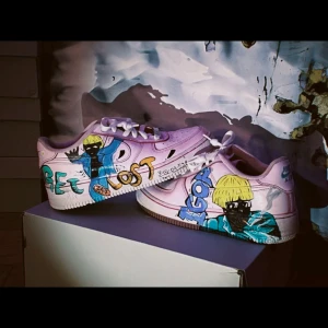 Handmålade sneakers med unikt motiv - Unika handmålade sneakers med färgglada illustrationer och text. Skorna har en bas i vitt med detaljer i rosa och blått. Perfekt för den som vill sticka ut med sin stil.