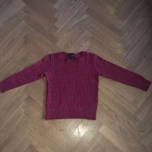 Röd stickad tröja: Ralph Lauren - Säljer en snygg vinröd stickad tröja från Ralph Lauren. Passar jättebra till jeans. Passar bra mellan åldern 14-16