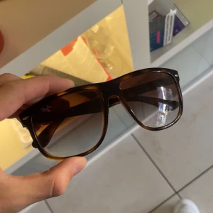 Bruna solglasögon från Ray-Ban - Snygga bruna solglasögon från Ray-Ban med en klassisk design. De har en bred båge och tonade glas som ger ett stilrent intryck. Perfekta för soliga dagar och en tidlös accessoar i garderoben. Skick 9/10 