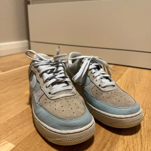 Nike Air Force i ljusblå och rosa/beige - Säljer ett par Nike Air Force sneakers i en snygg kombination av ljusblått och rosa/beige. Skorna har klassisk snörning och en bekväm passform. Perfekta för en stilren look💓