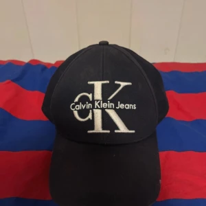 Svart keps från Calvin Klein Jeans - Snygg svart keps från Calvin Klein Jeans med justerbar rem baktill. Kepsen har en broderad logotyp framtill i vitt som ger en stilren look. Perfekt för en casual stil. Oanvänd. Säljer pga har en annan keps.