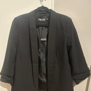 Svart kavaj från Pieces - Snygg svart kavaj från Pieces med trekvartsärmar. Perfekt för en stilren look. Kavajen har en klassisk design med en enkel krage och är tillverkad i ett mjukt material. Pris lapp kvar, aldrig använd💗🌸