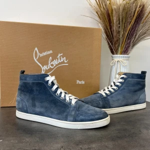 Blå mocka sneakers från Christian Louboutin - Snygga blå sneakers i mocka från Christian Louboutin med vit sula och snörning. Skorna har den ikoniska röda sulan som ger en lyxig touch. Perfekta för dig som vill ha stil och komfort i ett.