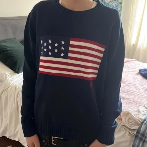 Mörkblå tröja med amerikansk flagga från Ralph Lauren - Säljer en mörkblå tröja från Ralph Lauren med en  amerikansk flagga på framsidan. Tröjan har sitter bra om du är en small, jag är en xs men den sitter fortfarande helt okej. Tröjan är riktigt stilig! Priset kan diskuteras.