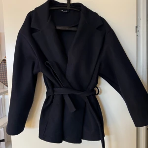 Marin blå kappa med bälte - Marin blå kappa från missay.se med bälte i midjan. Storlek M med siter som en S. Skriv privat för bild hur den sitter på.