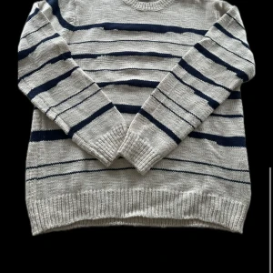 Beige och marinblå randig tröja från Casual Friday - Säljer en snygg beige tröja med marinblå ränder från Casual Friday. Tröjan är stickad och har en klassisk rund halsringning. Perfekt för en stilren och avslappnad look.