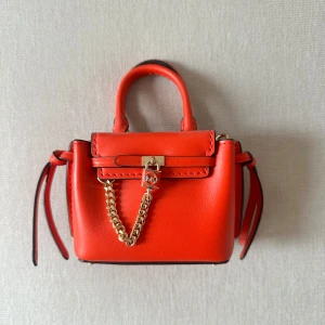 Michael kors mini bag - Michael kors micro väska som inte finns att köpa längre på hemsidor. Denna är köpt för 2 år sedan och använt endast 1 gång. Inga skador eller synligheter på användning. Skriv i chatten för väskans order historik och bevis på äkthet. Väskan heter Hamilton Legacy Micro Leather Belted Crossbody Bag, i färgen orange/röd. Köpt för 1300kr. Skriv gärna prisförslag. Bredd: ca 11cm