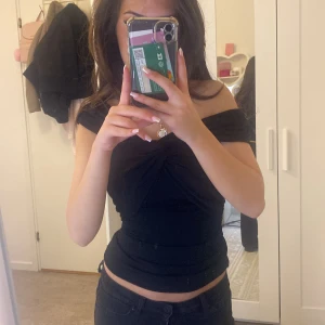 Svart offshoulder topp - Snygg svart offshoulder topp med knytdetalj framtill. Perfekt för en stilren och trendig look. Passar bra till både jeans och kjol. 