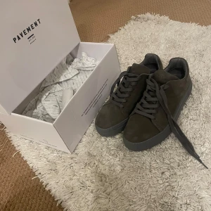 Grå sneakers från Pavement - Snygga grå sneakers från Pavement i mocka med snörning. Skorna har en rund tå och en robust sula för extra komfort. Och dessutom helt nya! 