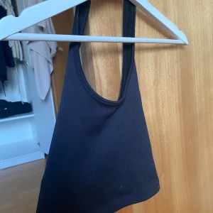 Svart ribbad linnetopp från Divided - Säljer en  svart ribbad linnetopp från H&M Divided. Toppen har en enkel design med smala axelband och rund halsringning.