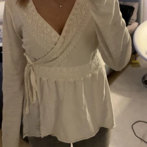 Vit omlottopp från Odd Molly - Säljer en snygg vit omlottopp från Odd Molly med spetsdetaljer och knytning i sidan💕