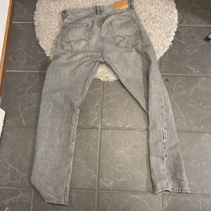 Grå jeansbyxor - Snygga grå jeansbyxor med klassisk femficksdesign och knappgylf. Perfekta för en avslappnad stil.