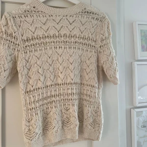 Beige stickad tröja från Zara - Säljer en beige stickad tröja från Zara med ett vackert spetsmönster. Tröjan har en rund hals och trekvartsärmar, perfekt för lager-på-lager under vår och sommar. Ett stilrent plagg som passar till många olika outfits!!🩷🩷