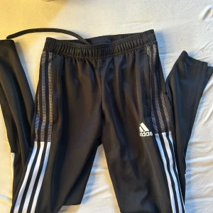  Adidas träningsbyxor  - Svarta träningsbyxor från Adidas i storlek XS. Byxorna har snörning i midjan och dragkedja vid bensluten. Tillverkade i mjukt och stretchigt polyestermaterial, perfekta för träning eller chill.