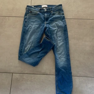 Blå skinny jeans från Calvin Klein - Snygga blå jeans från Calvin Klein med klassisk femficksdesign och diskret CK-logga bak i midjan. Jeansen har skinny passform och är tillverkade i mjukt denimtyg som sitter tajt längs benen. Perfekta för en stilren och modern look.              Storlek: W30L30