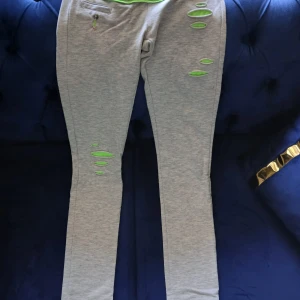 Grå mjukisbyxor med neon-detaljer - Grå mjukisbyxor från G-Star Raw med slim passform och coola neongröna detaljer. Byxorna har slitna partier med neonfoder, fickor fram och bak samt elastisk midja. Perfekta för en chill och trendig look har aldrig använts men har tyvärr inte kvittot