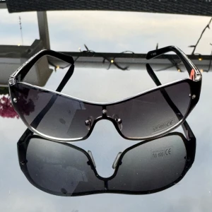Svarta sportiga solglasögon UV400 - NYA svarta solglasögon med breda bågar och shield-formade linser. Glasen är tonade i grått och har UV400-skydd. Hämtas i Hägersten. 