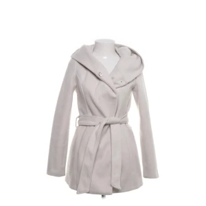 Vit kappa med huva från Amisu, stl 34 - Snygg vit kappa från Amisu med huva och bälte i midjan. Jackan har omlottknäppning med knappar och är tillverkad i mjuk polyester. Perfekt för dig som gillar stilren och clean look med lite extra edge tack vare huvan. Skriv privat för fler bilder💕 