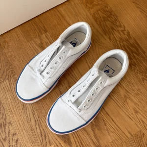 Vita Vans sneakers med regnbågsrand - Vita Vans sneakers med färgglad rand i blått, rött och gult runt sulan. Storlek 36, aldrig använda 