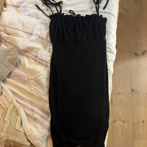 Svart festklänning - Svart festklänning från Nelly med smala axelband som man knyter. Den har även scrunch upptill. Den är i strl xs och i fint skick💕