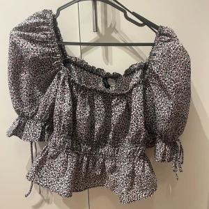 Blommig blus  - Supersöt blommig blus från Divided i svart och rosa med smockad midja i croppad modell😊.Perfekt för dig som gillar söta toppar. 💕💕