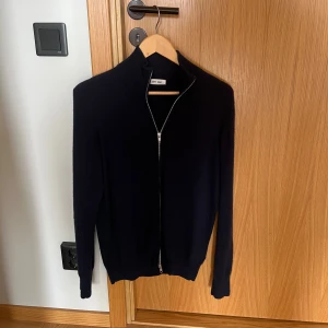 Mörkblå kashmirkofta från Soft Goat - Snygg mörkblå kofta från Soft Goat i mjuk kashmir. Tröjan är i stort sett oanvänd och tröjan är i nyskick. Storleken är M. Nypris 2895.