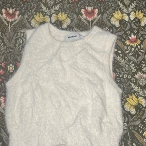 Vit fluffig ärmlös topp Weekday - Supermjuk och fluffig vit topp från Weekday med rund halsringning och ärmlös design. Perfekt för att skapa en cool och trendig look, lätt att matcha med både jeans och kjol. Materialet känns mysigt och ger en unik textur.