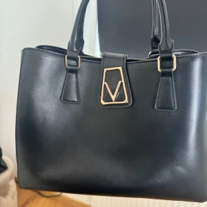 Svart Valentinoväska - Snygg svart handväska från Valentino med stilrena gulddetaljer och V-logga framtill💕💕