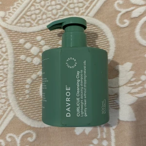 Davroe CURLiCUE Cleansing Clay - Grön pumpflaska med 300 ml Davroe CURLiCUE Cleansing Clay, ett lätt detox-schampo för skonsam rengöring av håret utan att ta bort naturliga oljor. Vegansk och cruelty free formula, perfekt för dig som vill ha fräscht och återfuktat hår.