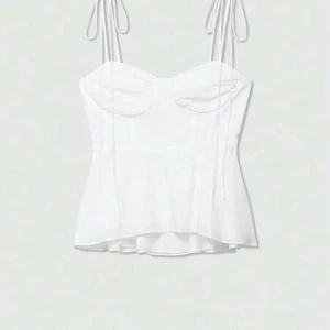 Vit linnetopp med knytband - Supersöt vit linnetopp med tunna axelband som knyts upptill. Toppen har en lätt utsvängd form och markerade kupor för en feminin look. 